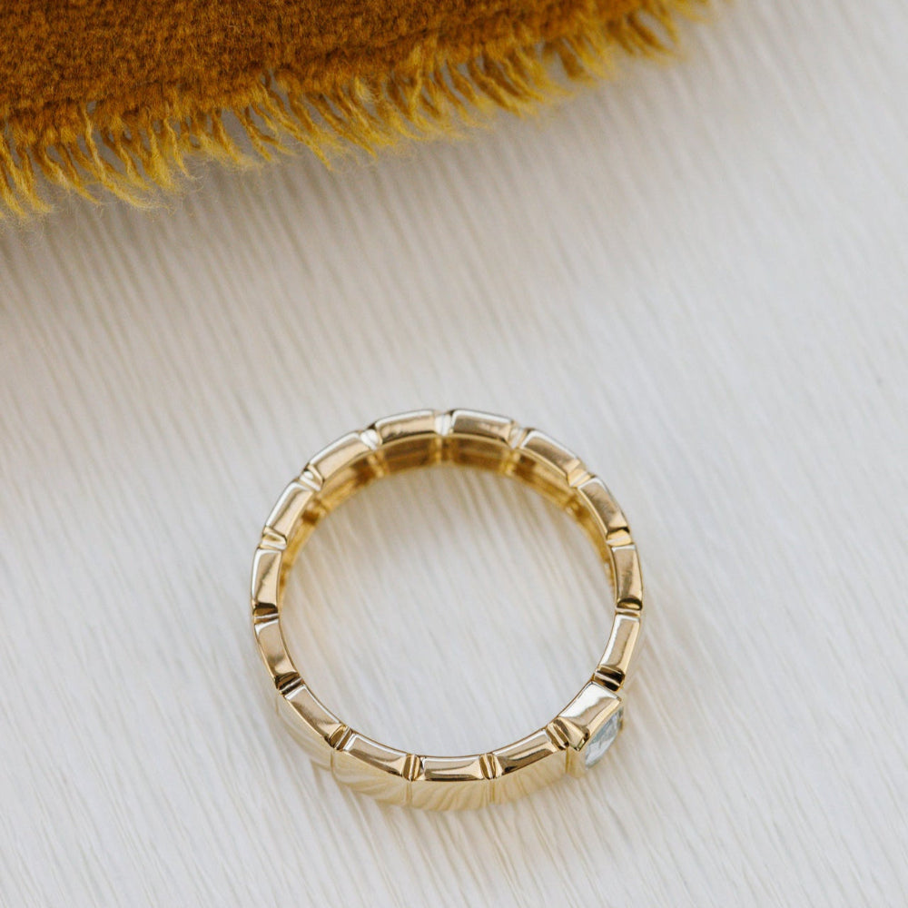 Gold ring with a textured band on a light fabric background