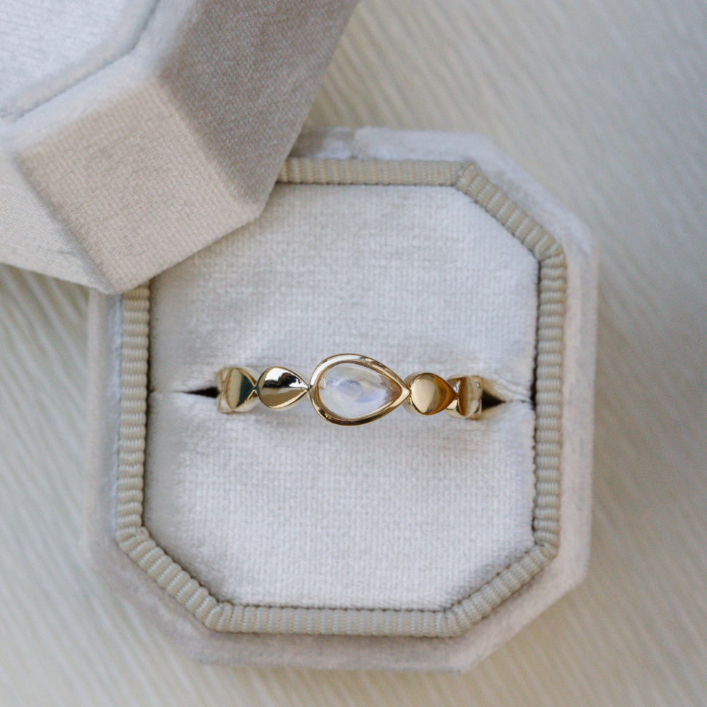 Gold ring with a central gemstone in a jewelry box on a textured surface