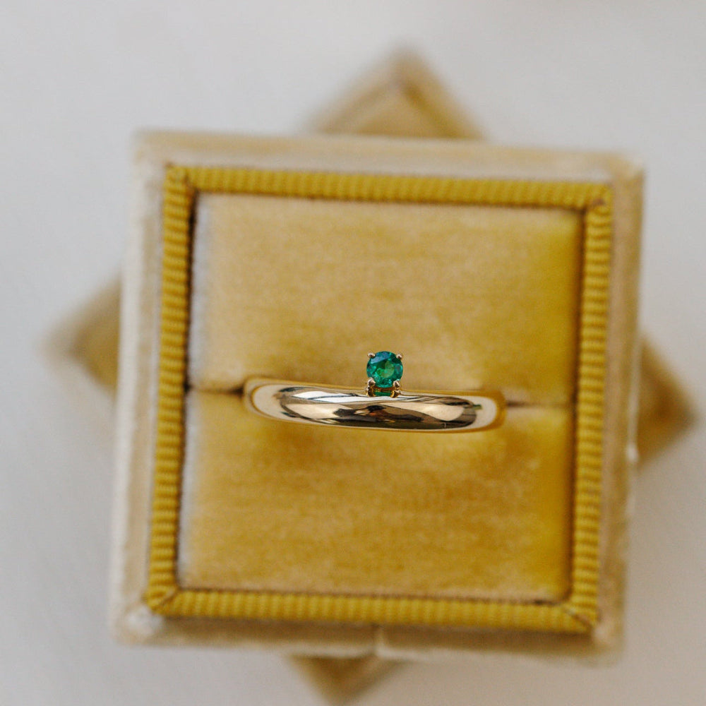 Gold ring with a green gemstone in a yellow velvet box