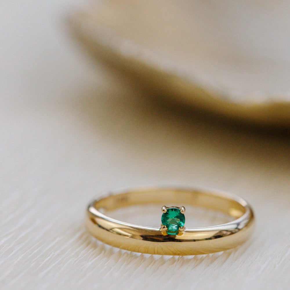 Gold ring with a green gemstone on a light background