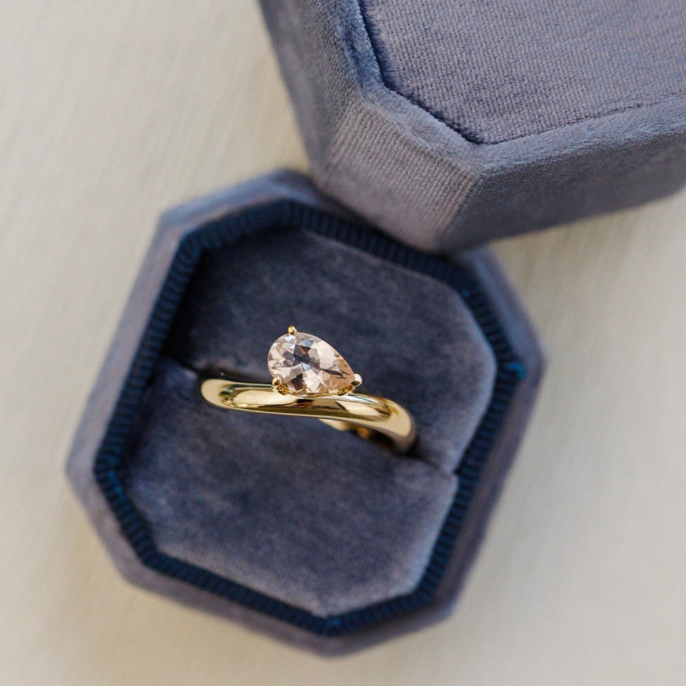 Gold ring with a pear-shaped diamond in a blue jewelry box