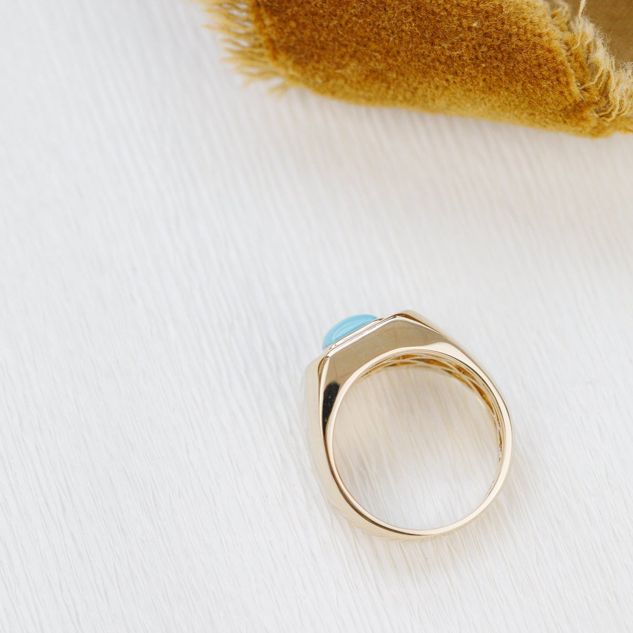 Gold ring with a blue stone on a white background
