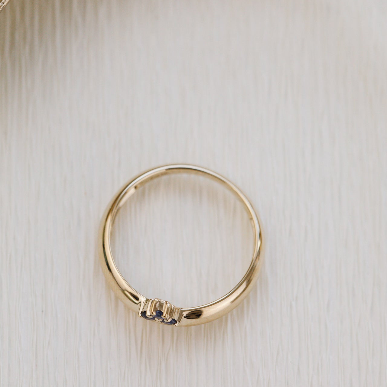 Gold ring with a small gemstone on a light wooden surface
