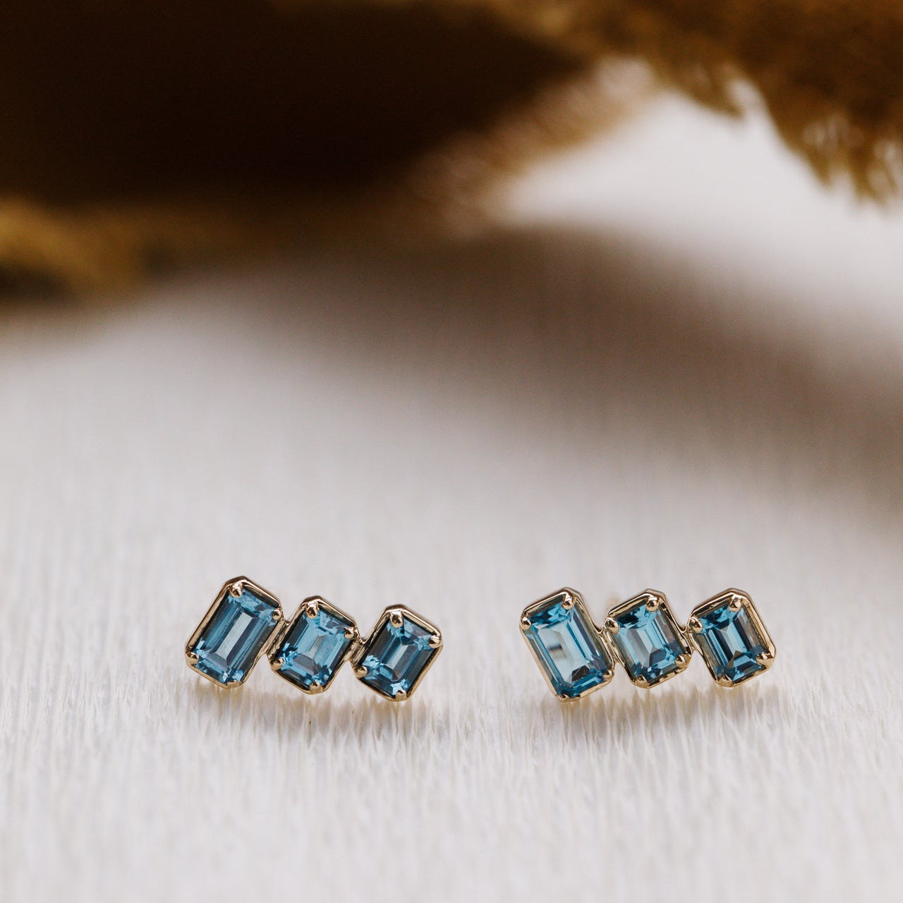 Pair of gold earrings with blue gemstones on a textured surface