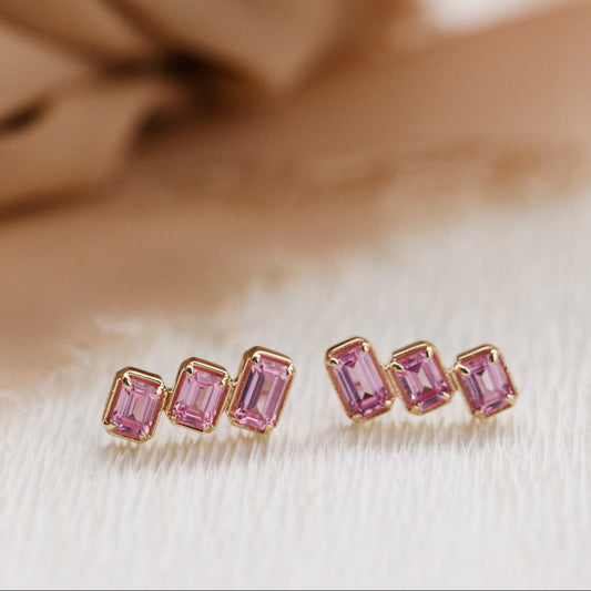 Pair of pink gemstone earrings on a beige fabric background