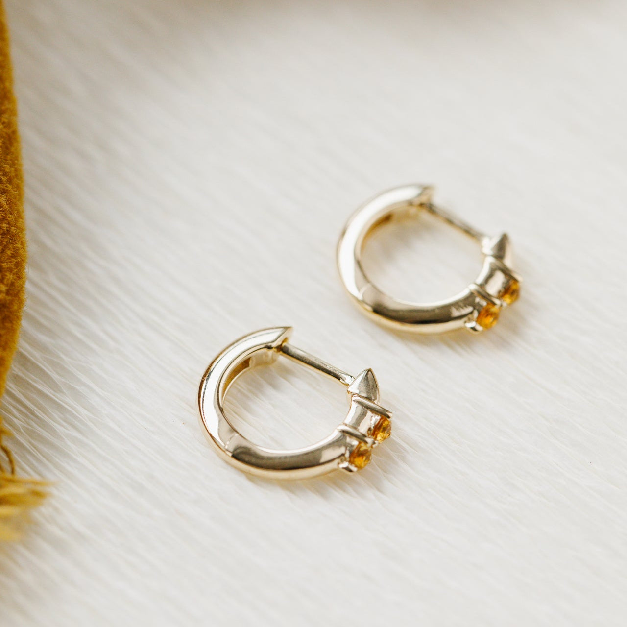 Gold hoop earrings with embedded stones on a light background
