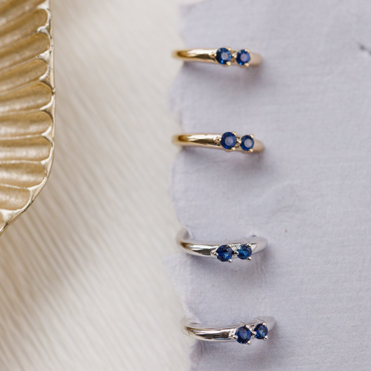 Set of gold and silver rings with blue gemstones on a textured surface