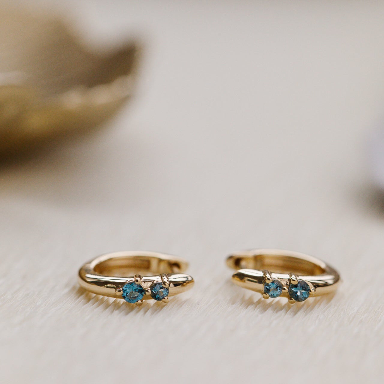 Two gold rings with blue gemstones on a light background