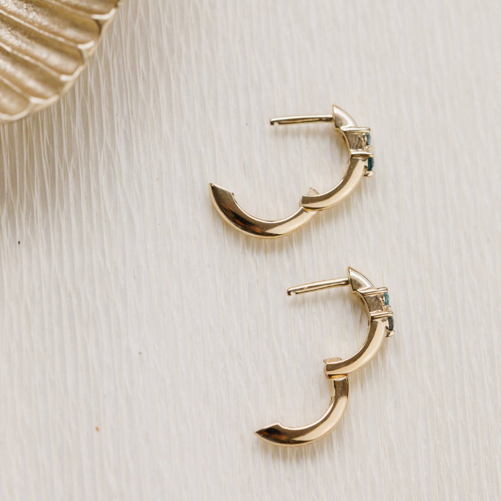 Gold hoop earrings on a textured beige surface