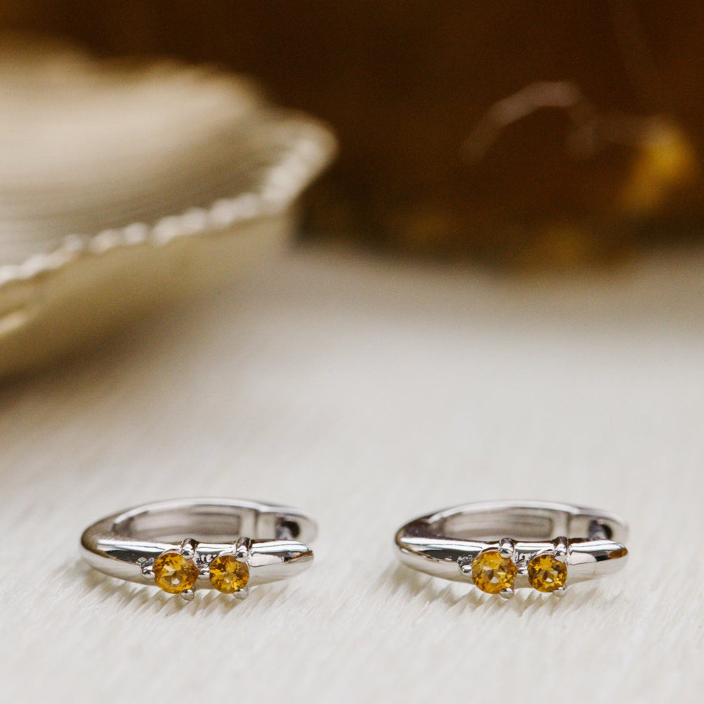 Two white gold with yellow gemstones on a textured surface.