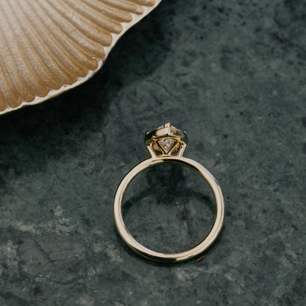 Gold ring with a diamond on a textured green surface
