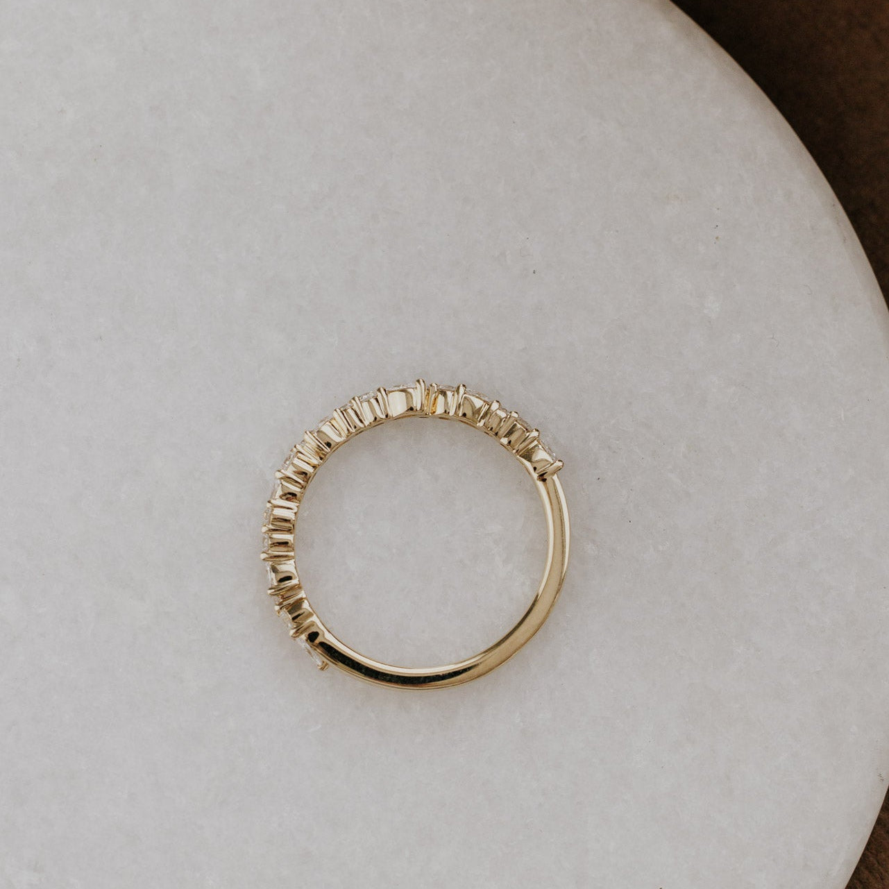 Mini Natalie wedding band with diamonds on a light gray surface.