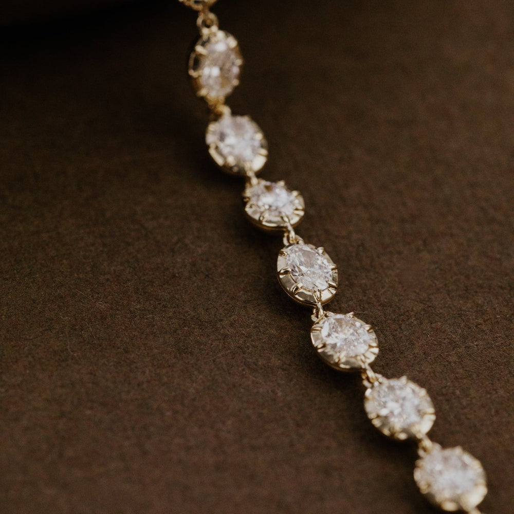 Diamond tennis bracelet on a dark surface.