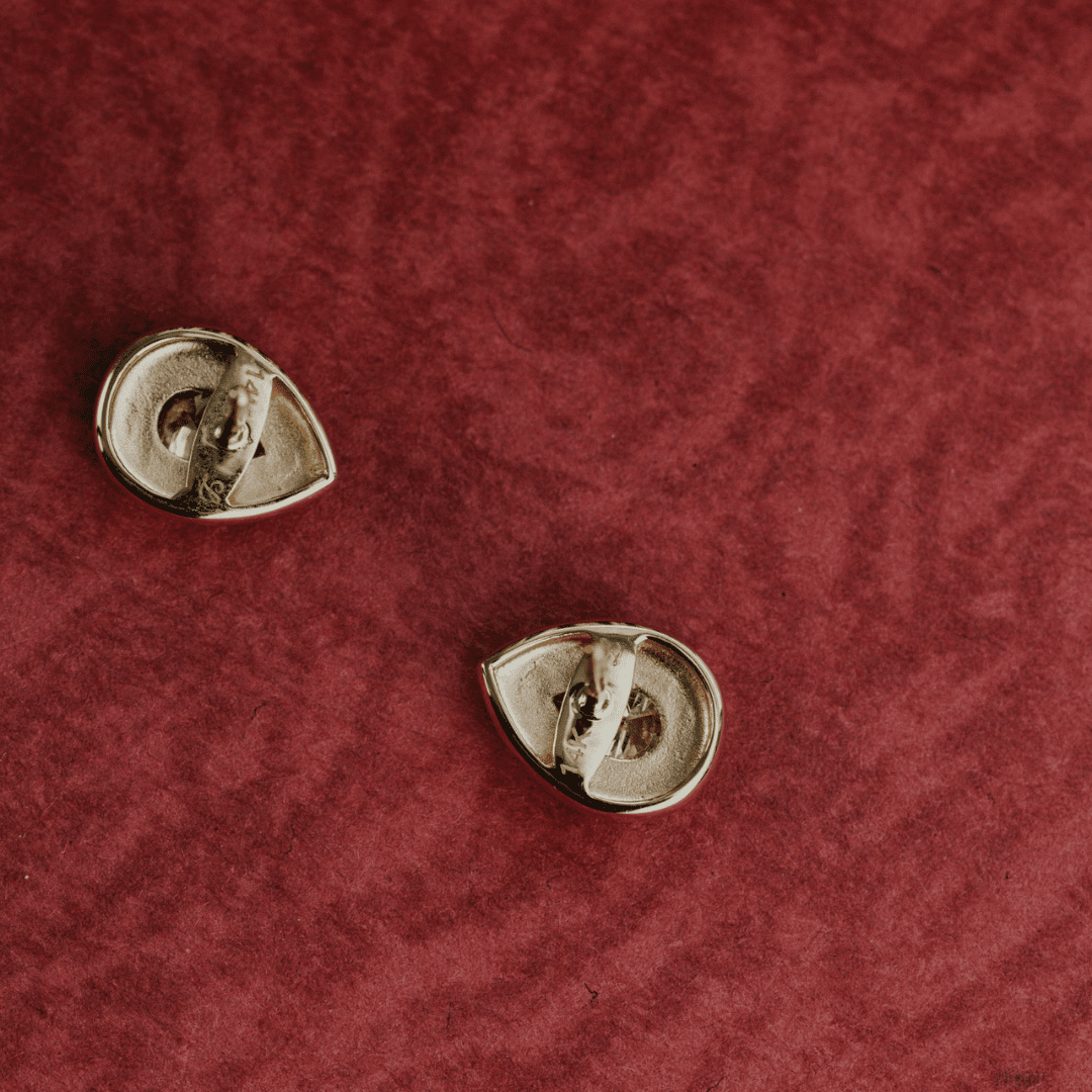 14k gold lab grown diamond earrings showcased on a textured red surface showing the backside of the earring.
