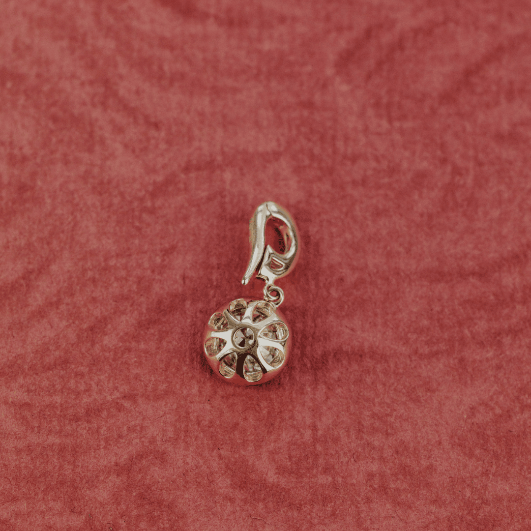 The backside of a 14k gold round-cut diamond with Black Rhodium clip pendant featured on a textured red surface.