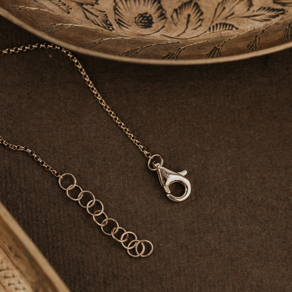 Gold bracelet with clasp on a textured brown surface.