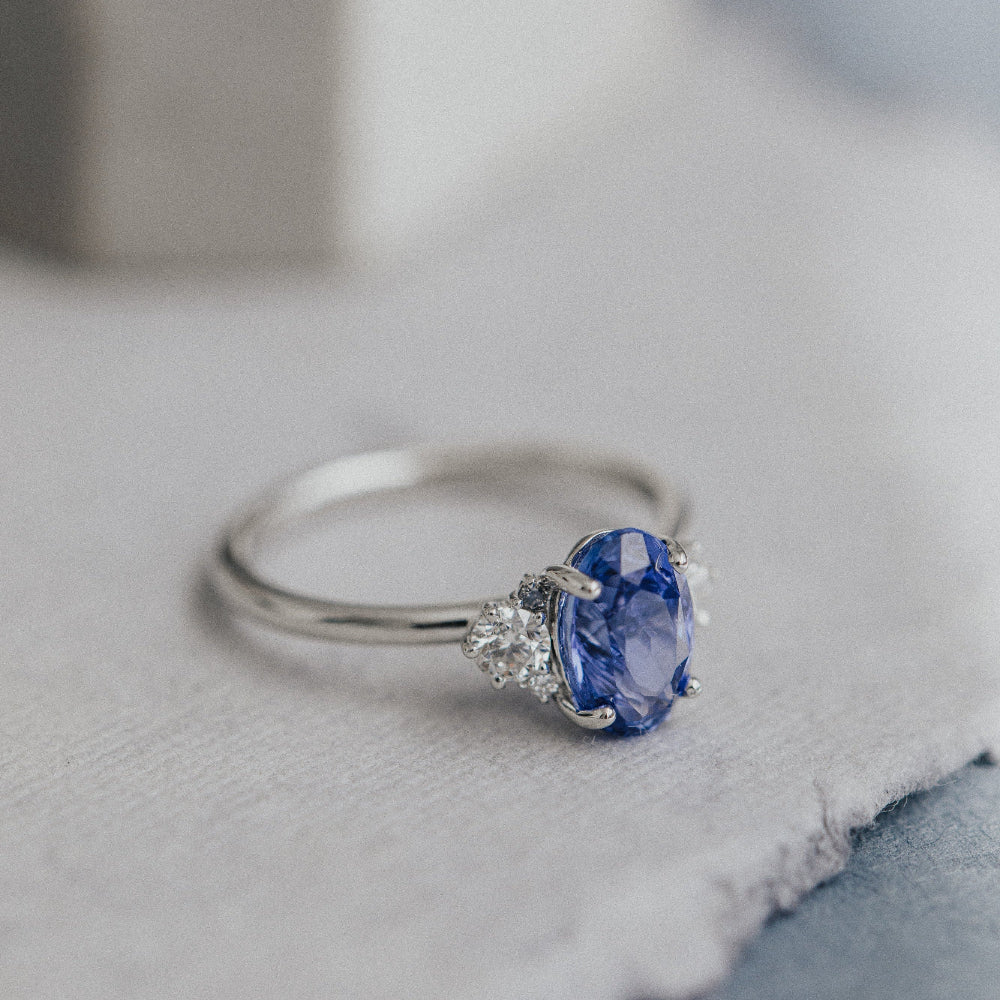 White gold ring with a blue sapphire on a textured surface