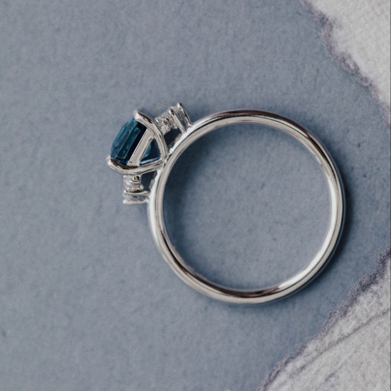 White Gold ring with a blue Montana Sapphire on a textured gray surface