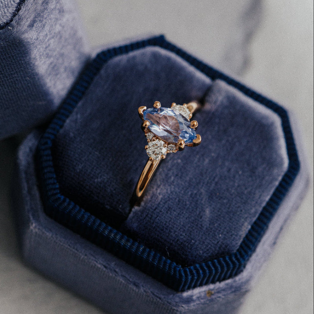 Sapphire ring in a blue velvet box on a light gray surface