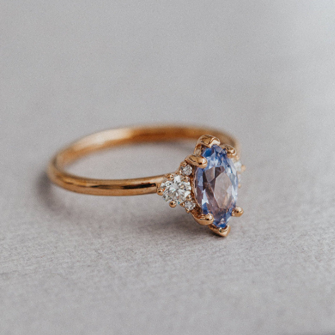 Gold ring with a blue sapphire gemstone on a gray surface