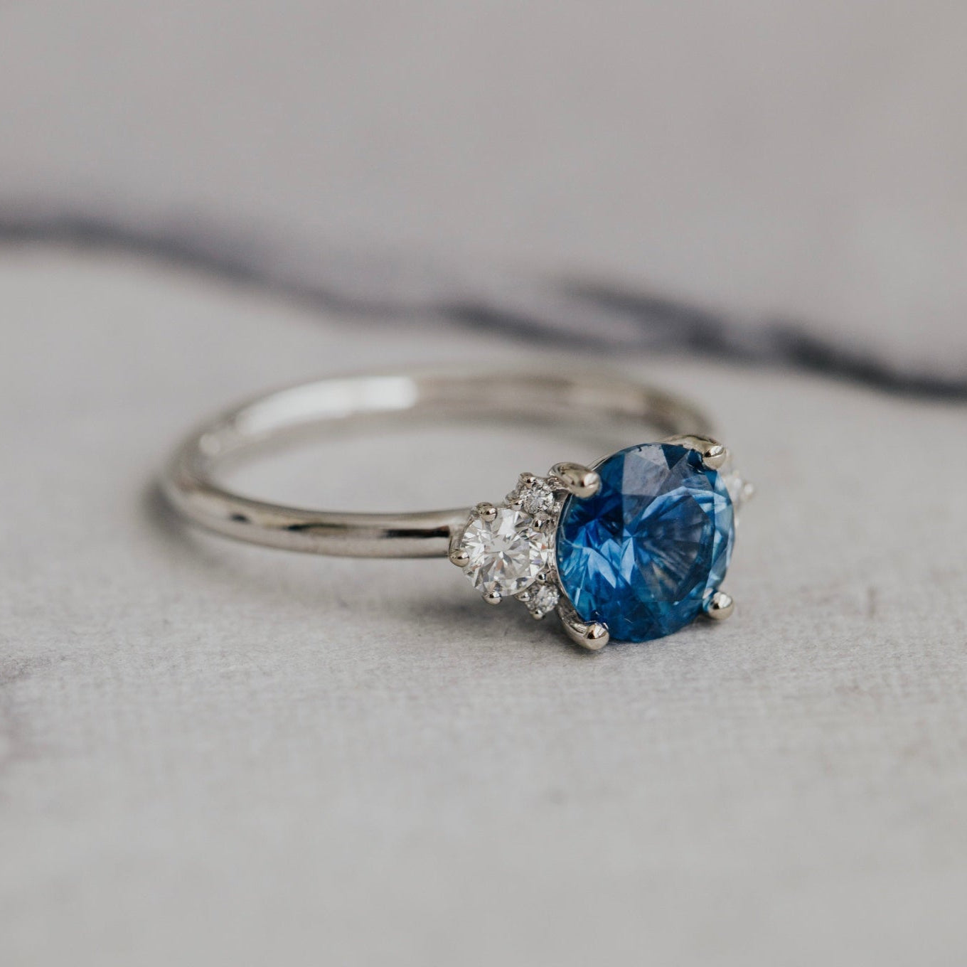 White gold ring with a  blue Montana Sapphire on a marble surface