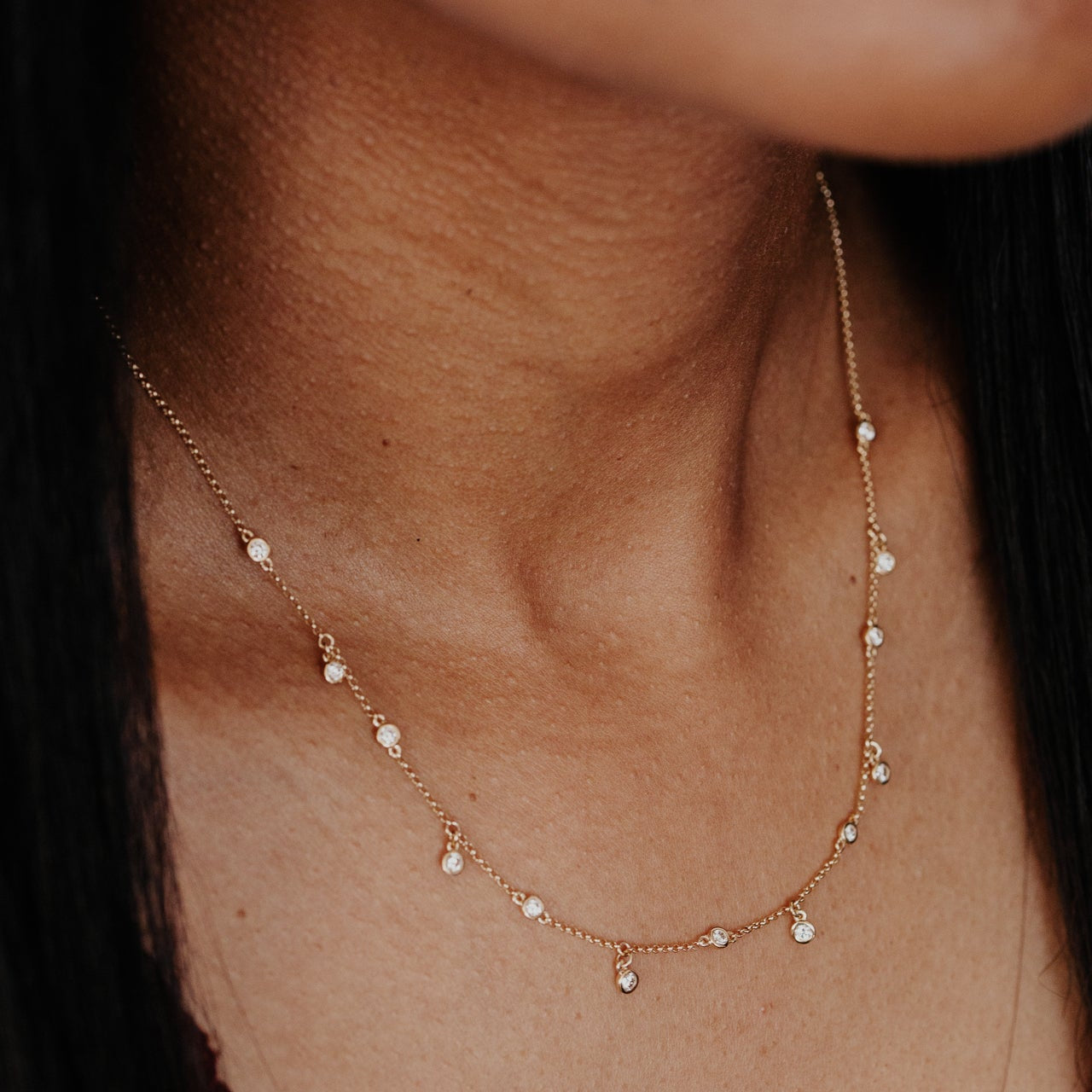 Delicate gold necklace with diamond stones on a person's neck