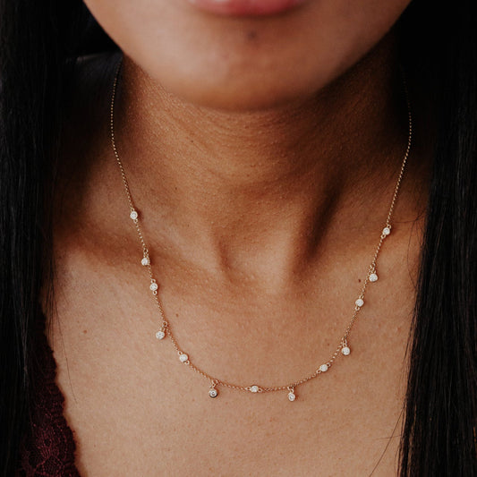 Close-up of a delicate diamond necklace on a person's neck with a blurred background