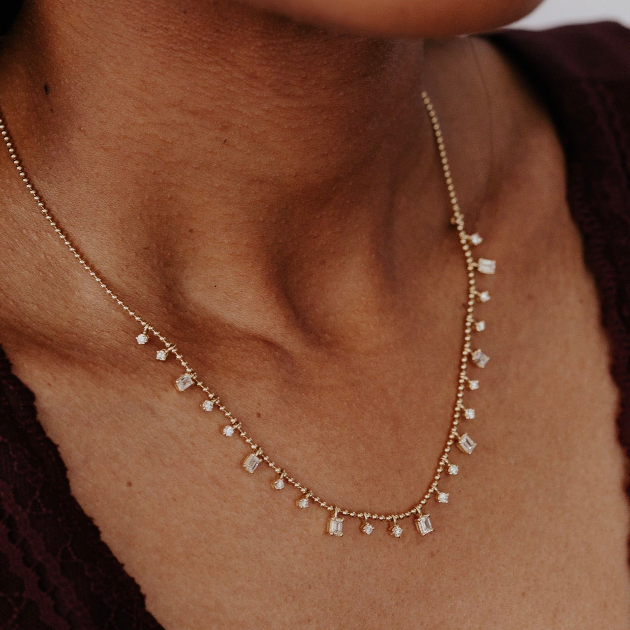 Close-up of a person wearing a delicate gold diamond necklace with small stones.