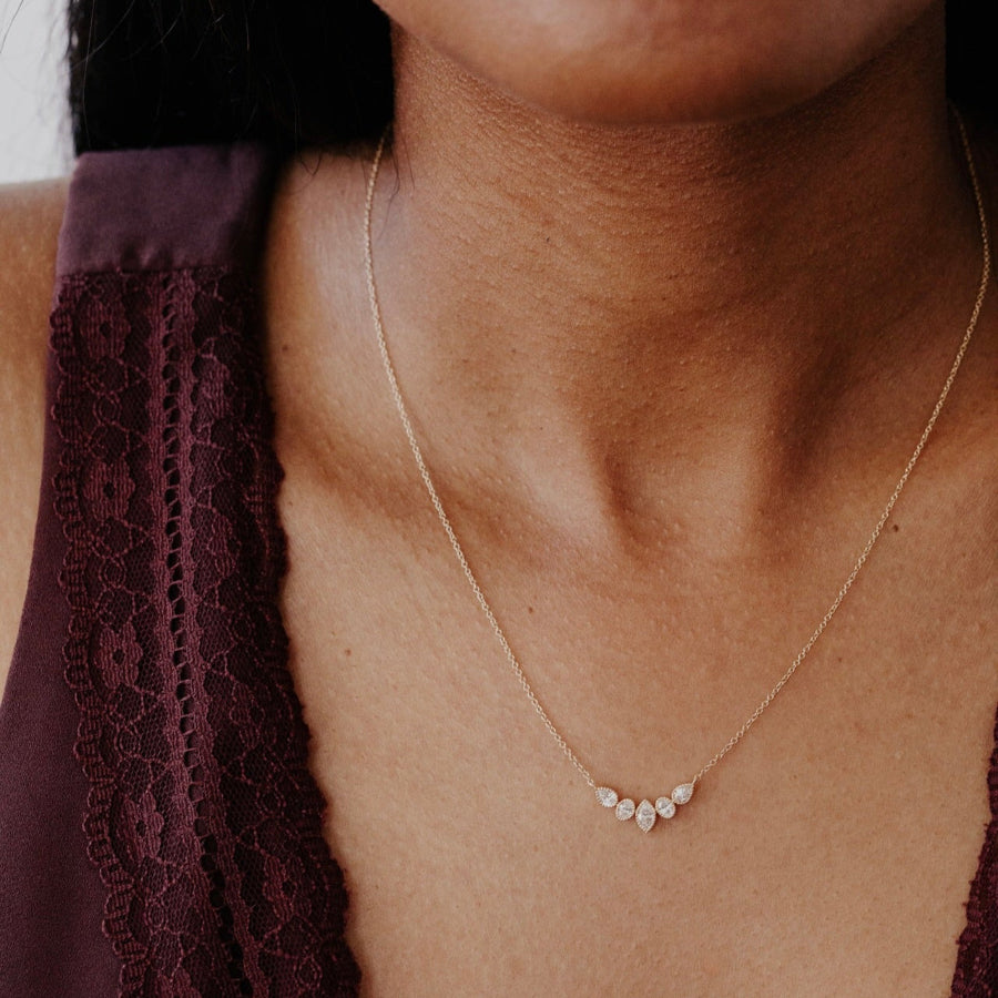 Close-up of a person wearing a delicate gold necklace with small diamond stones.