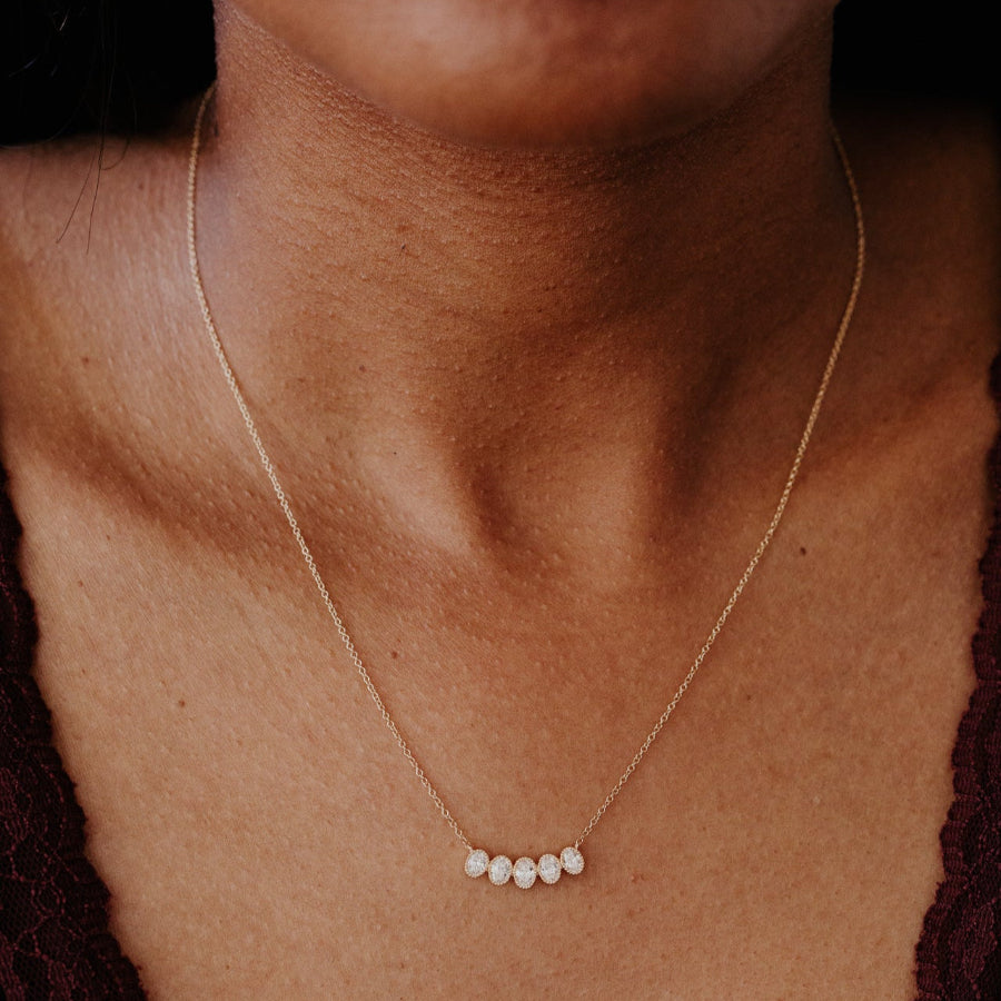 Gold necklace with oval diamonds on a person's neck