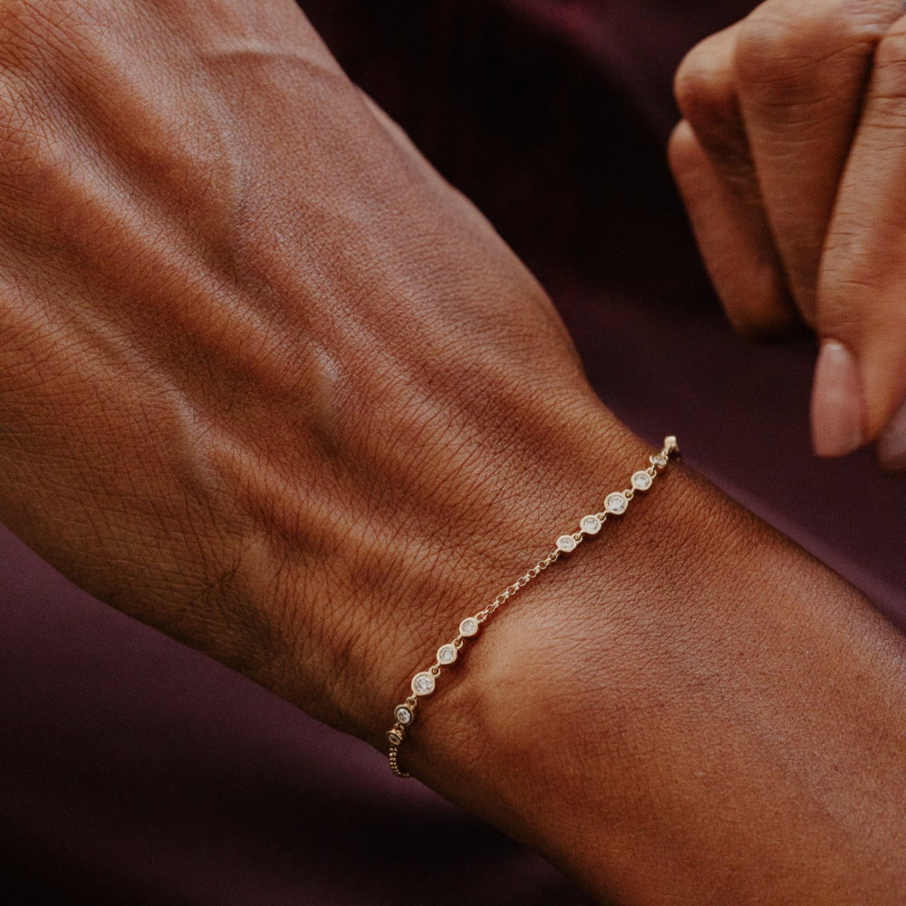 Close-up of a wrist wearing a delicate bracelet on a dark background