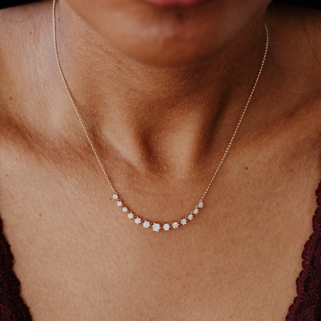 Close-up of a person wearing a delicate gold necklace with small stones.