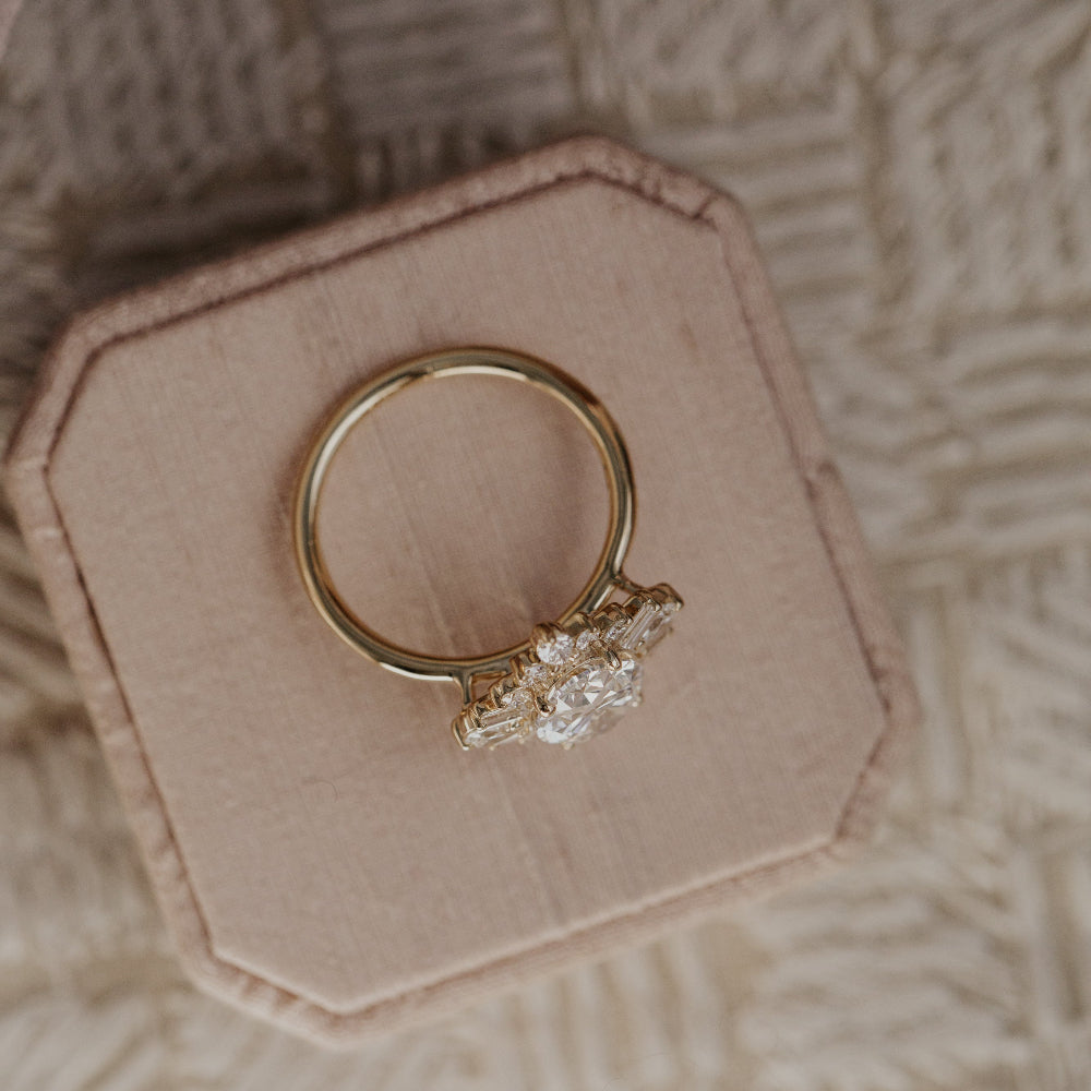 Top-down view of a yellow gold engagement ring with a diamond on a pink ring box