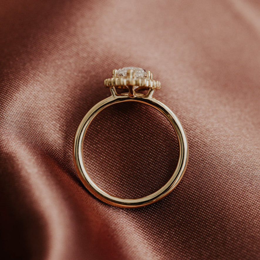 Top-down view of a yellow gold diamond engagement ring on a rose silk surface