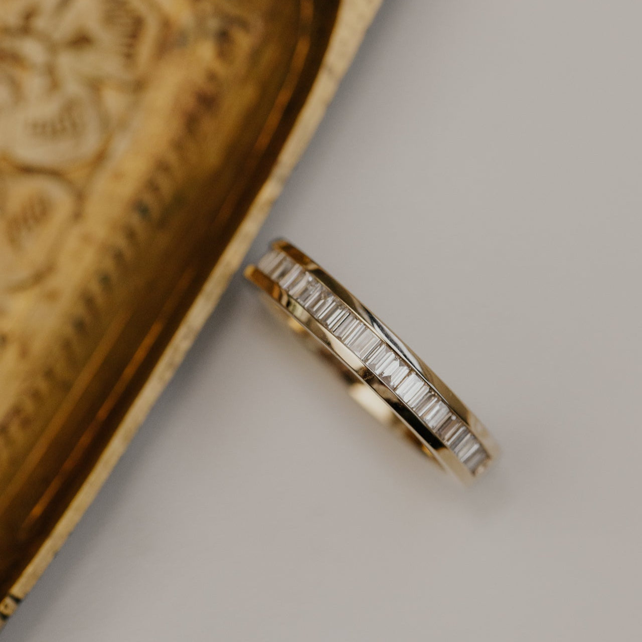Gold wedding band with diamond accents on a textured surface