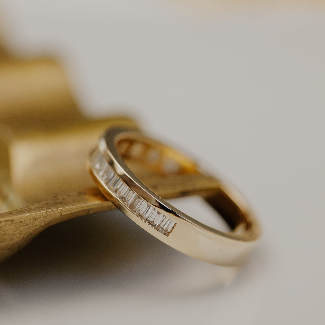 Gold wedding band with diamond accents on a blurred background