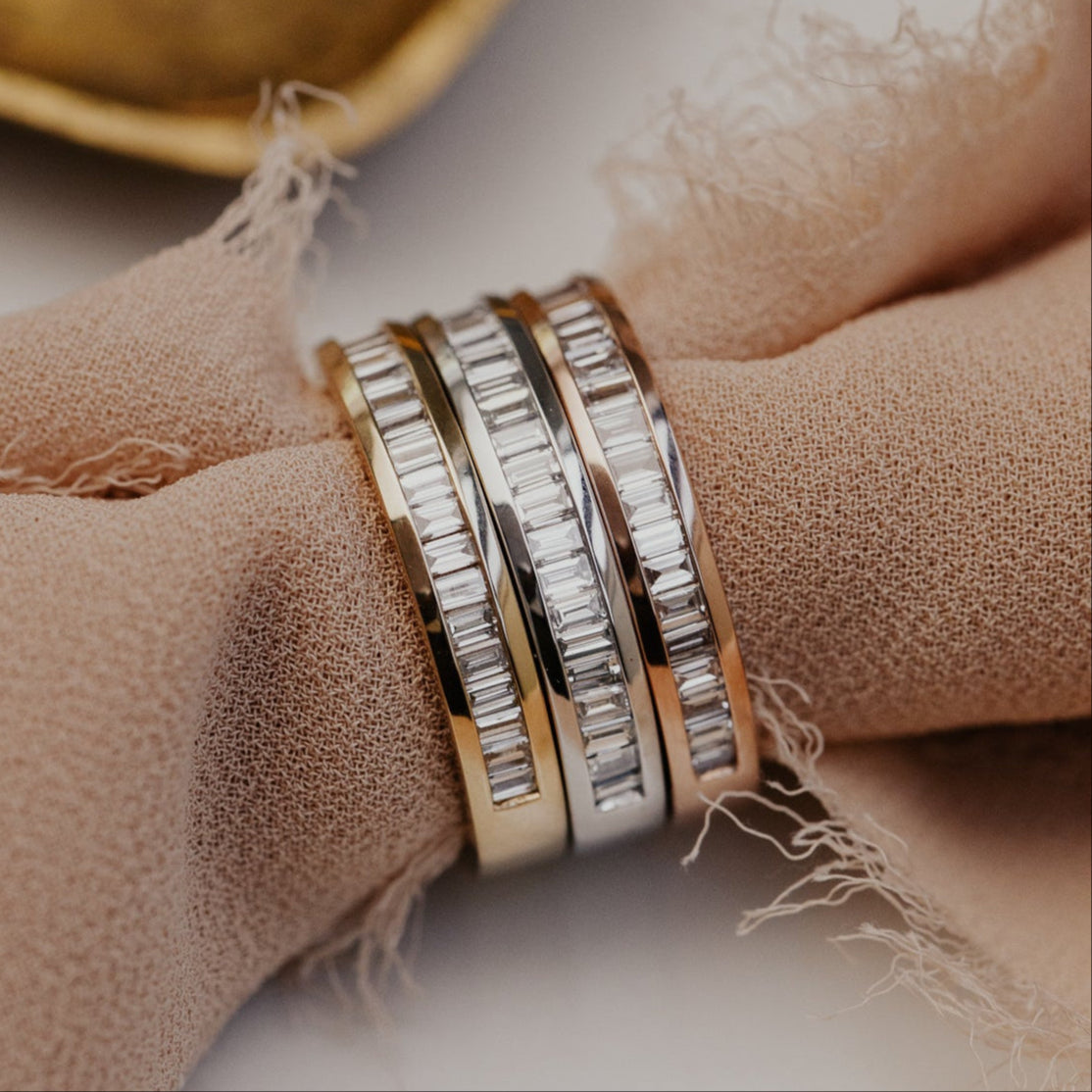 Three gold diamond wedding bands  stacked on a beige fabric surface
