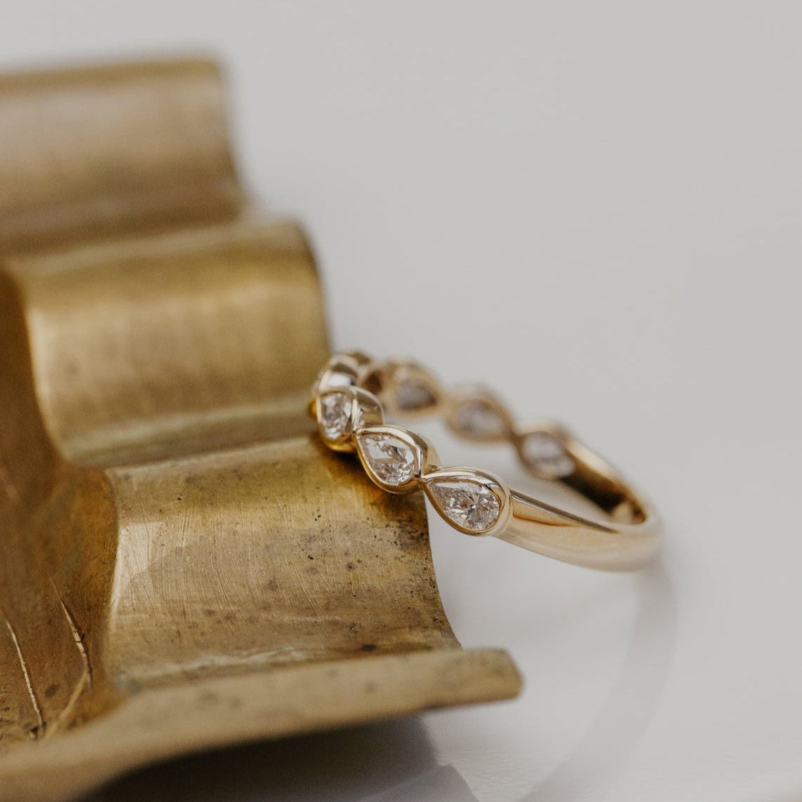 Gold wedding band with pear-shaped diamonds on a wooden stand