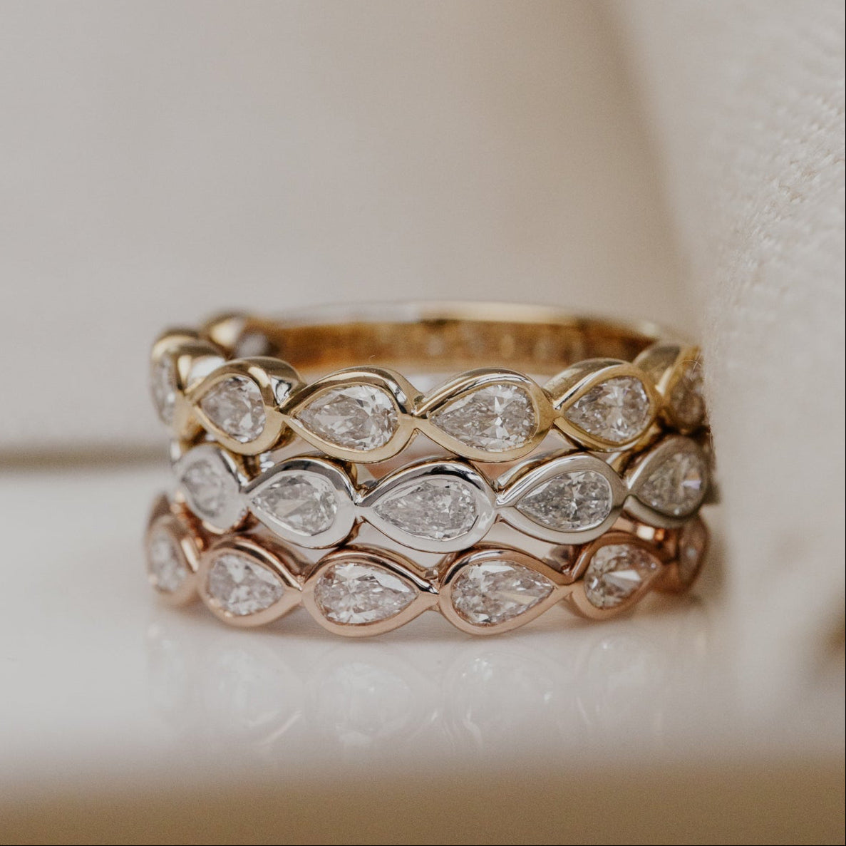 Gold wedding band with diamond accents on a soft beige background