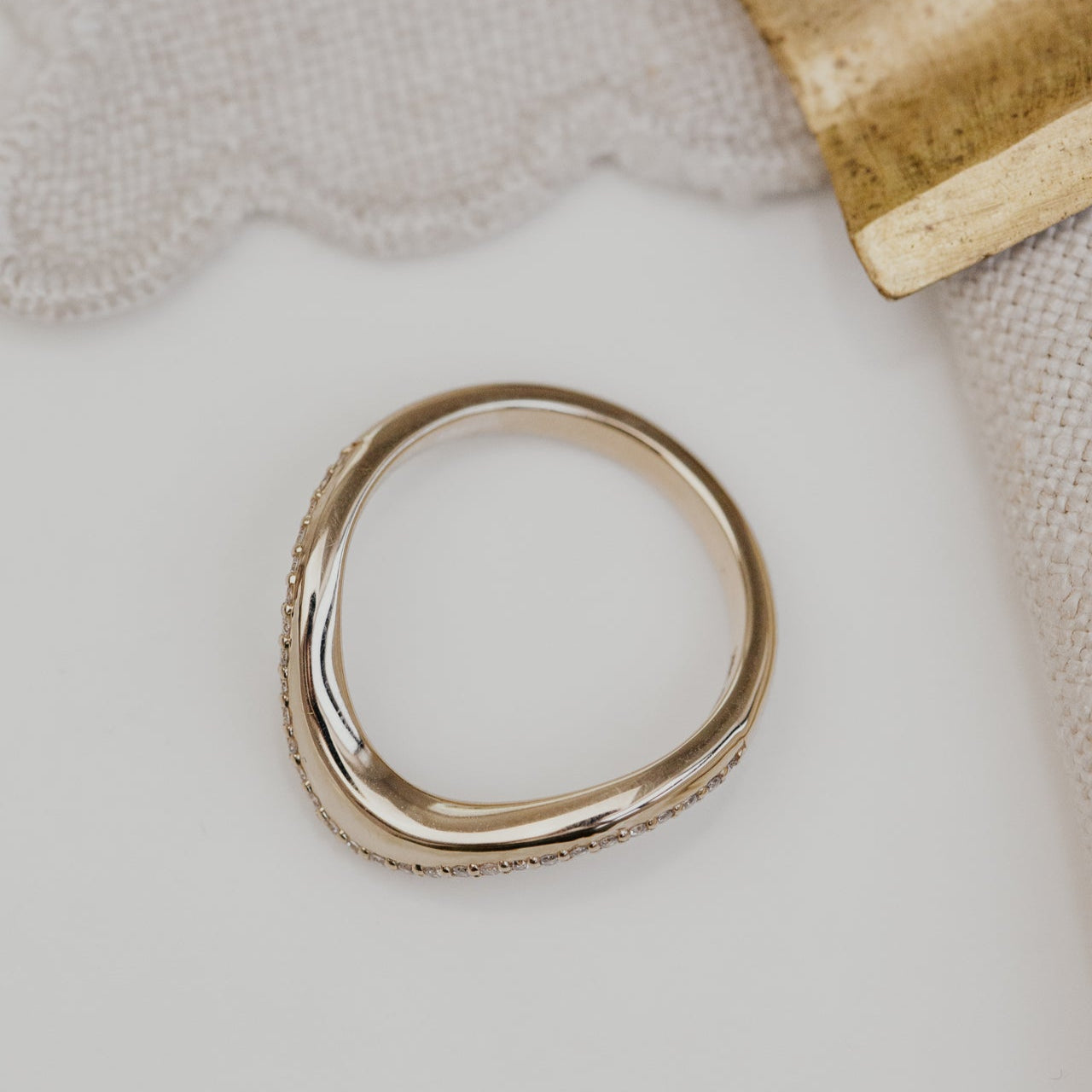 Gold wedding band on a textured surface with a neutral background