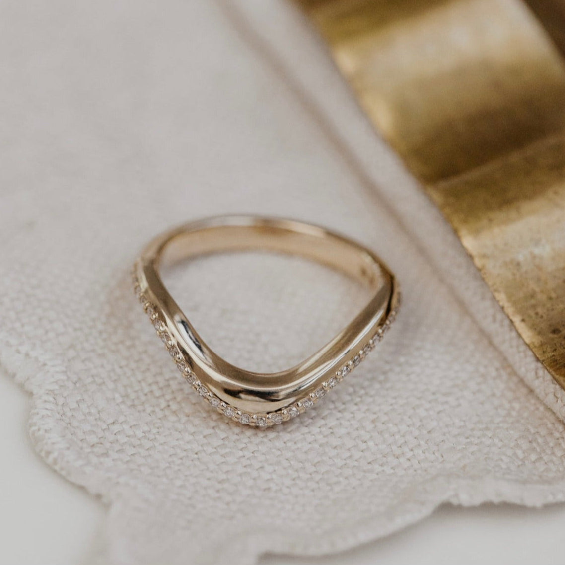 Gold wedding band with diamond accents on a textured surface