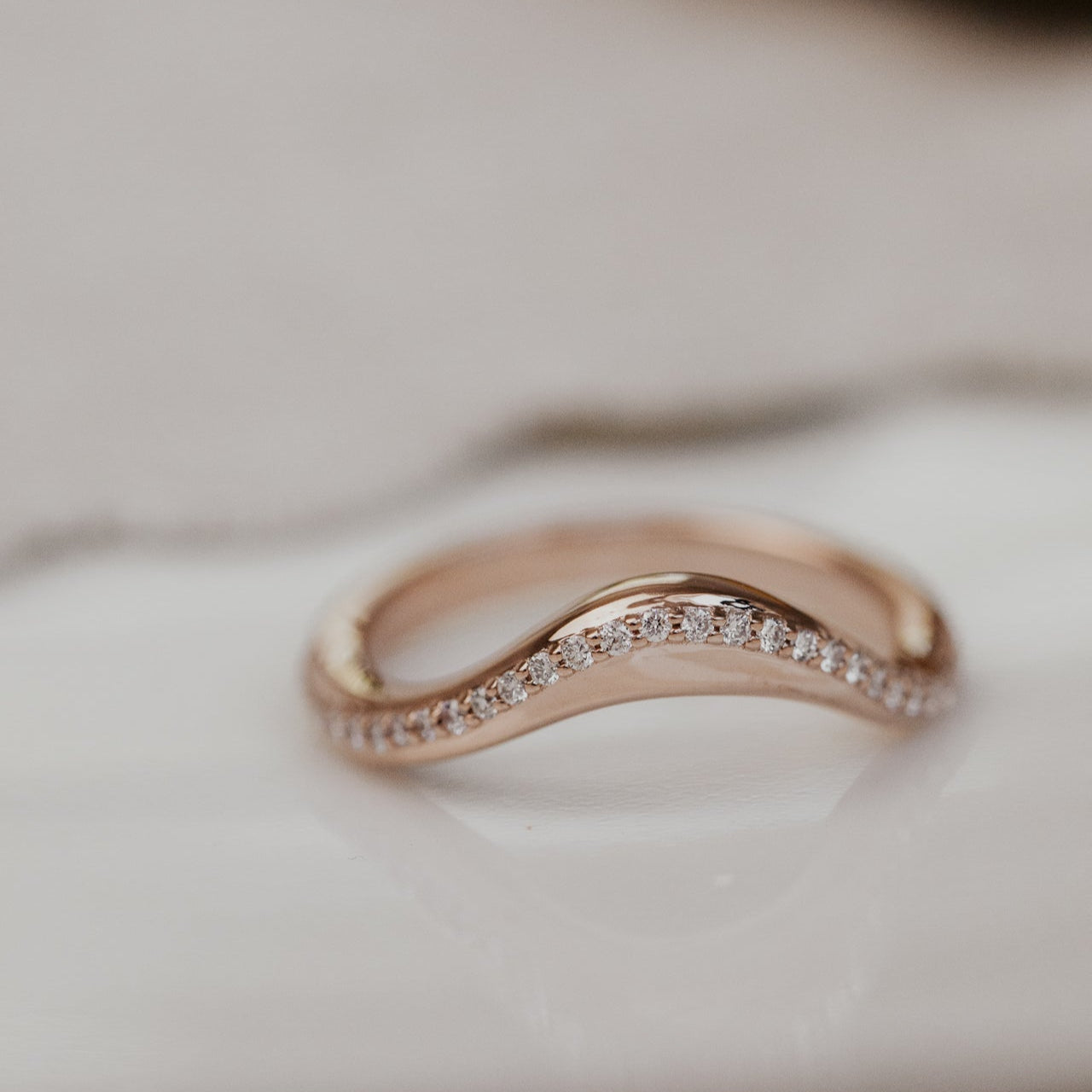 Rose gold wedding band with pave diamonds on a soft surface