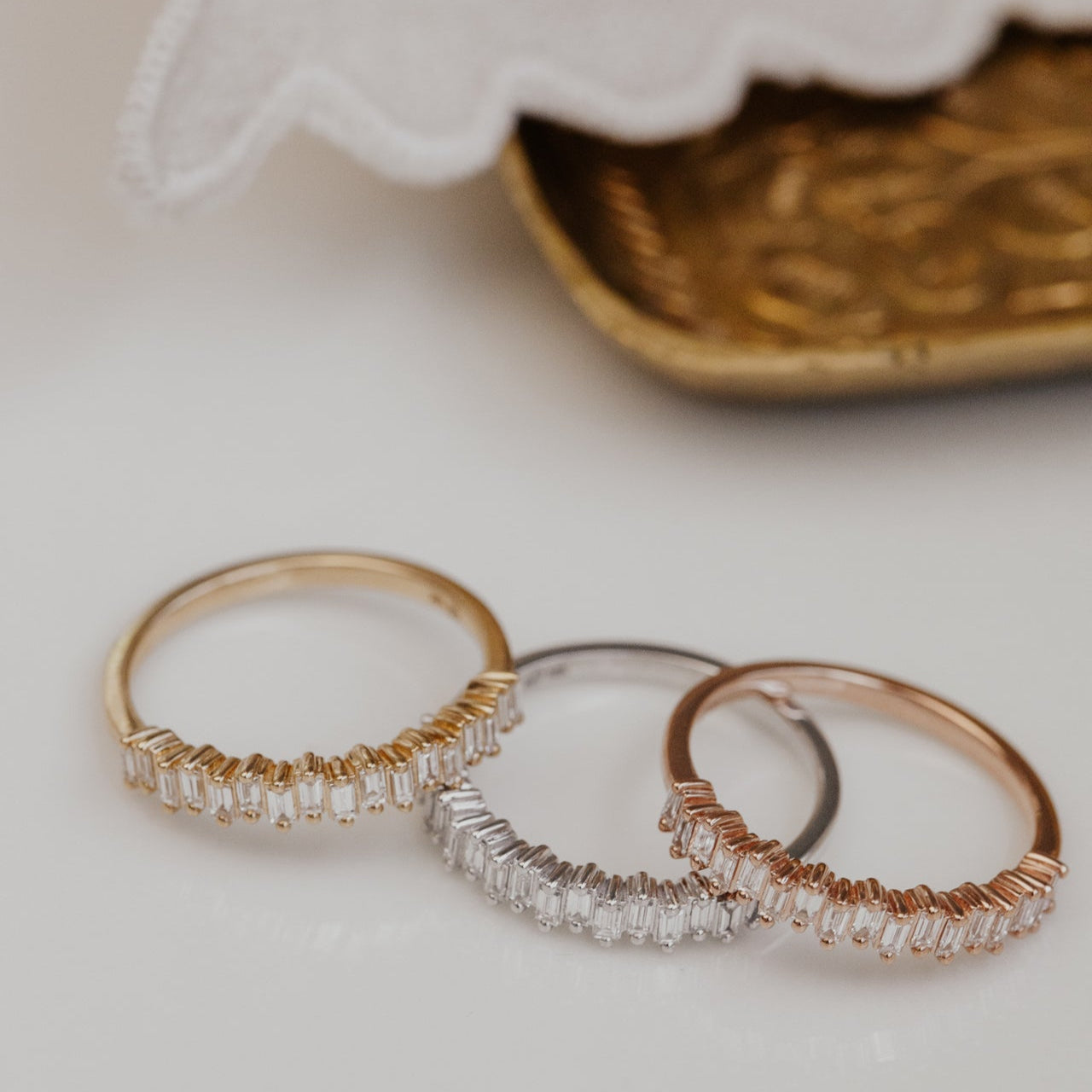 3 gold wedding bands with diamond accents on a white surface.