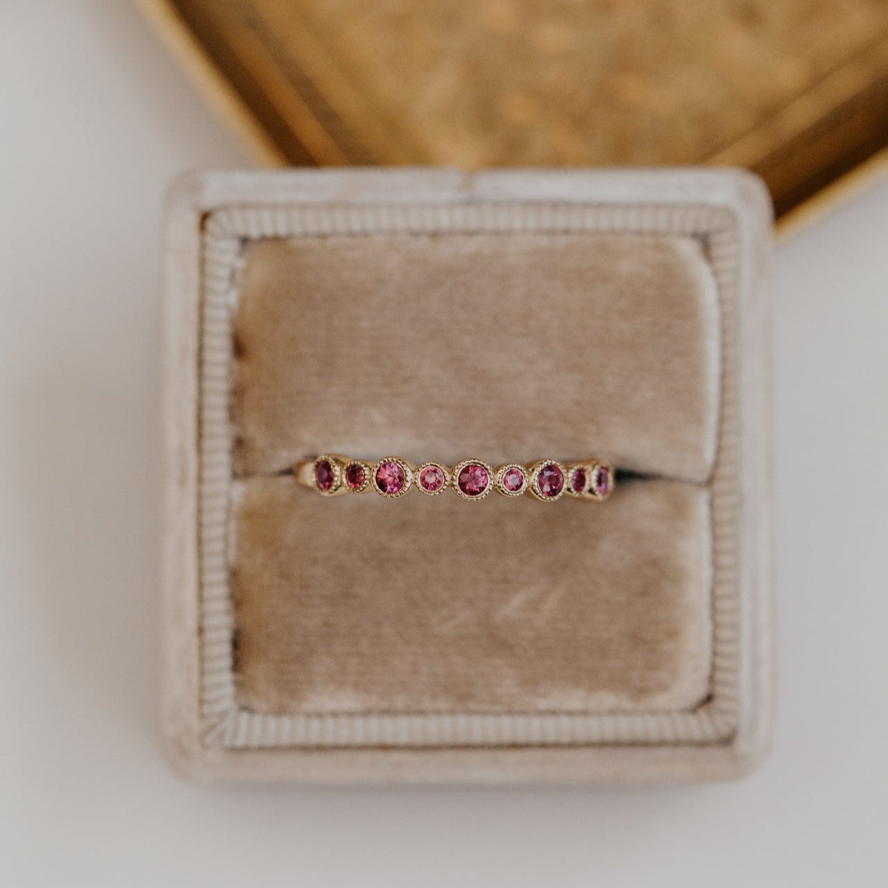 Jewelry box with a ruby wedding band featuring small gemstones on a neutral background