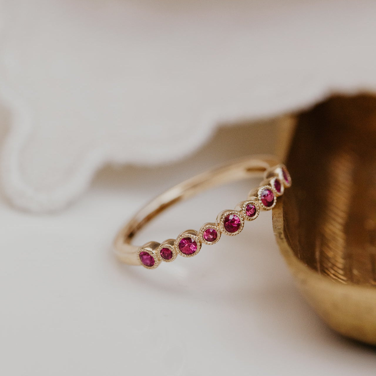 Gold band with red ruby gemstones on a white surface