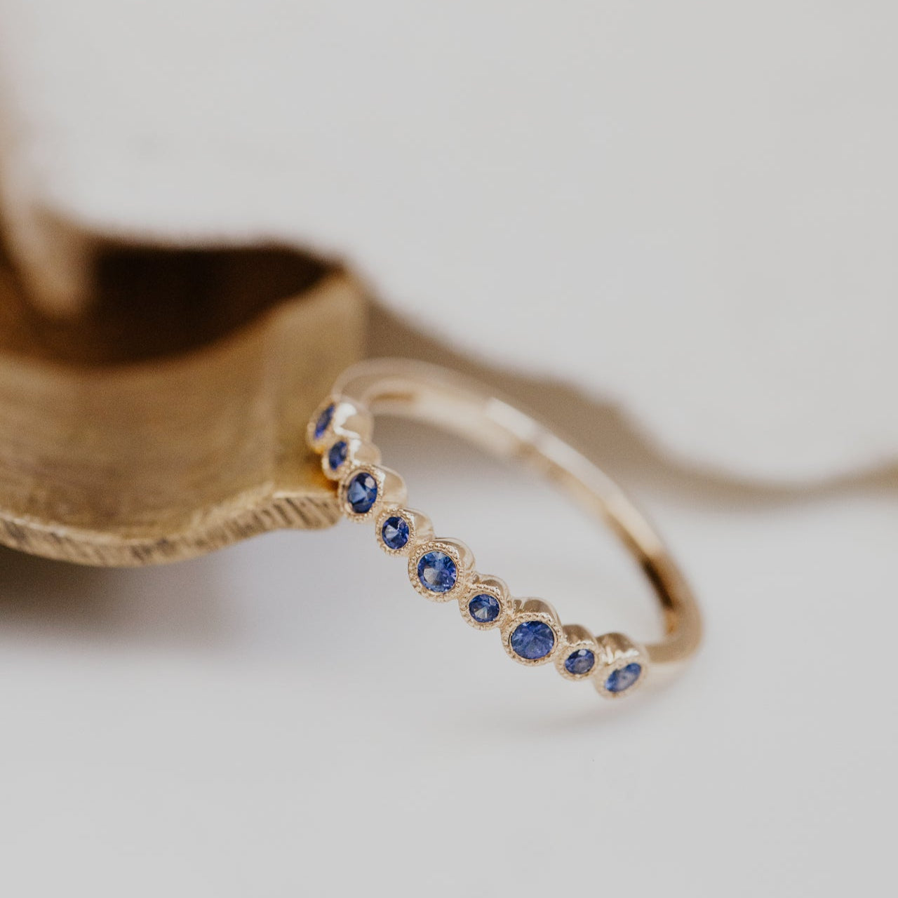 Gold wedding band with blue sapphires on a light background