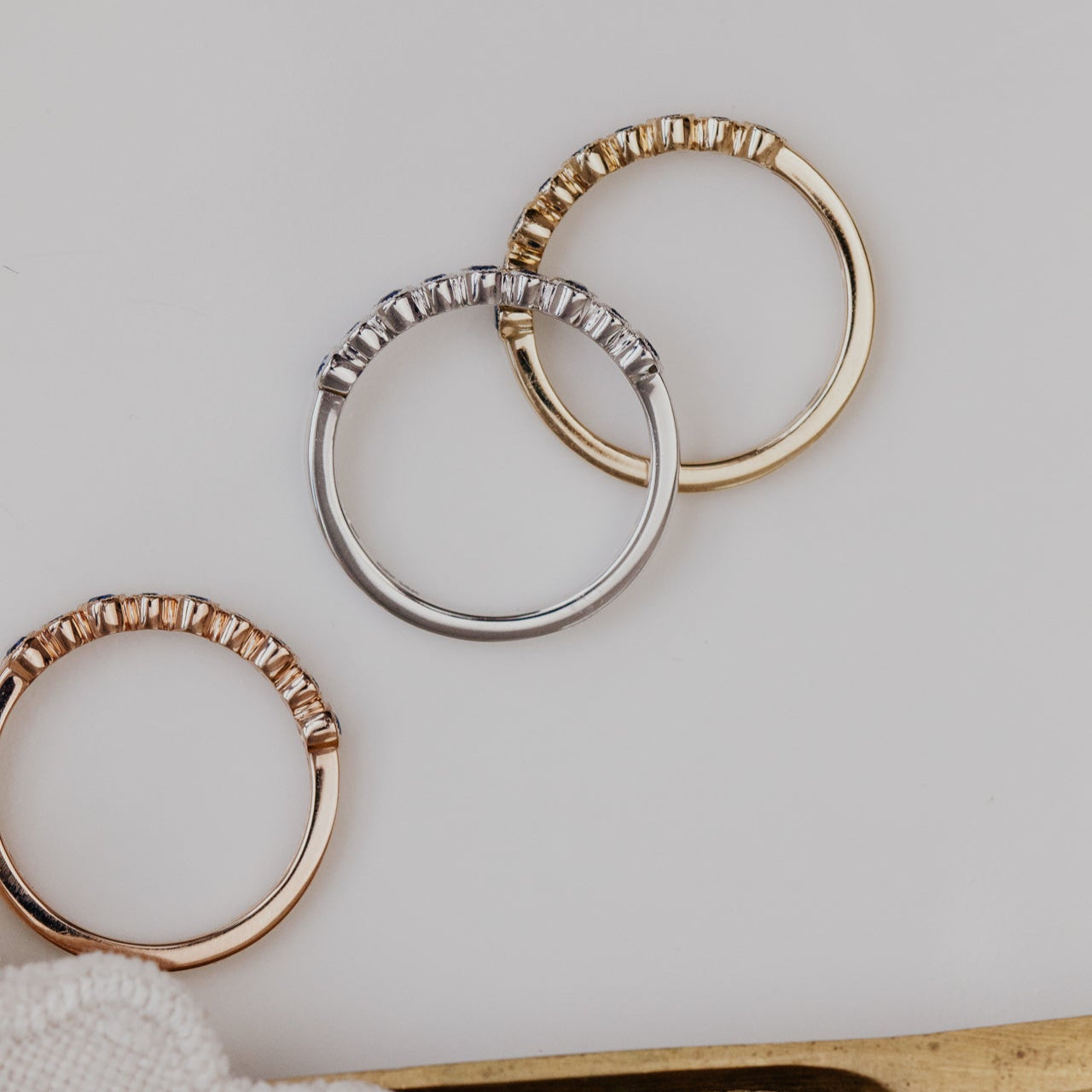 Three gold wedding bands on a light gray surface