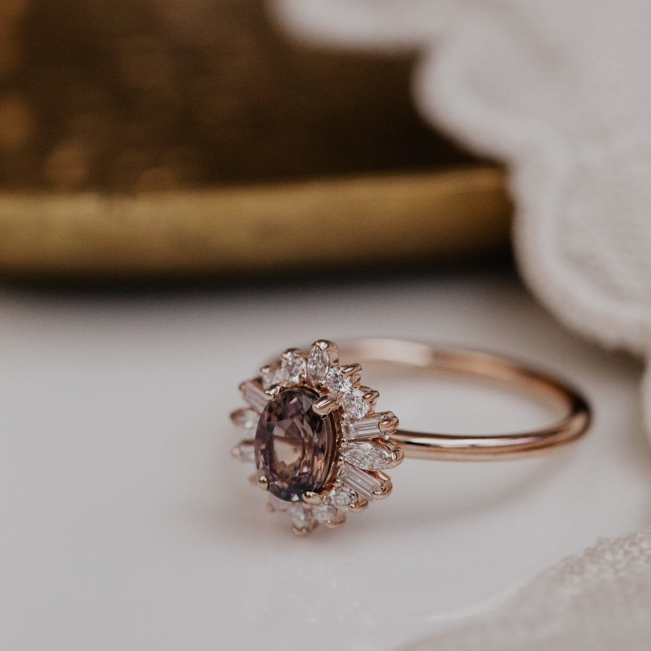 Rose gold ring with a purple sapphire gemstone and diamond halo  on a neutral background