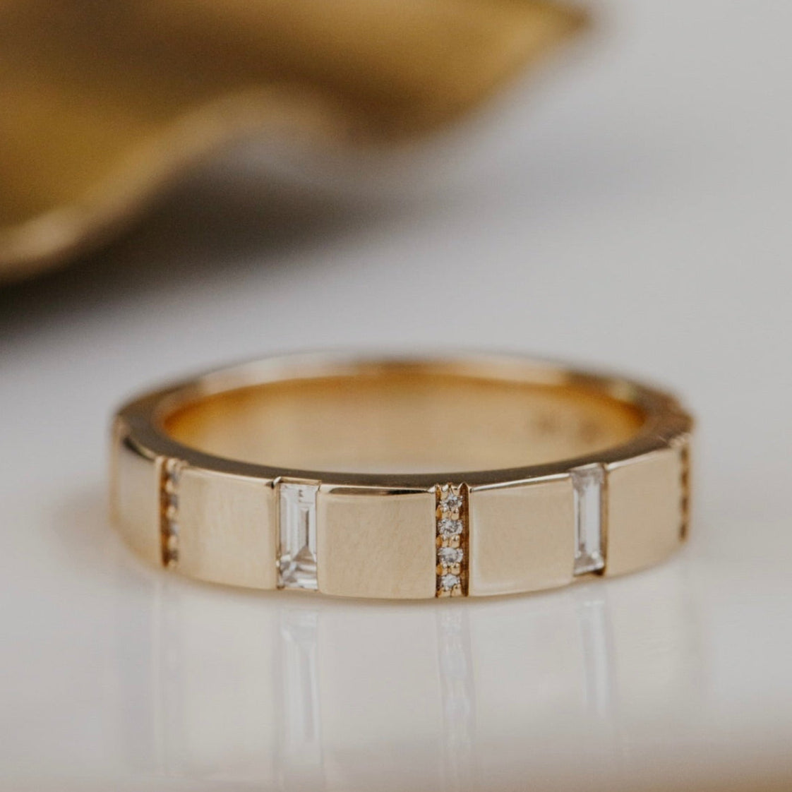 Gold wedding band with embedded diamonds on a light background