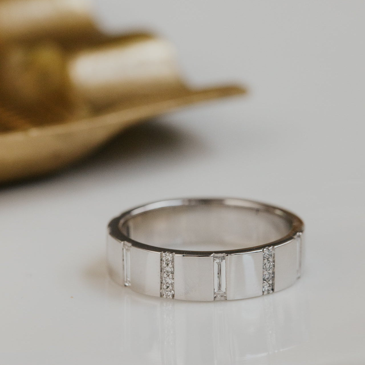 White gold wedding band with small stones on a light surface